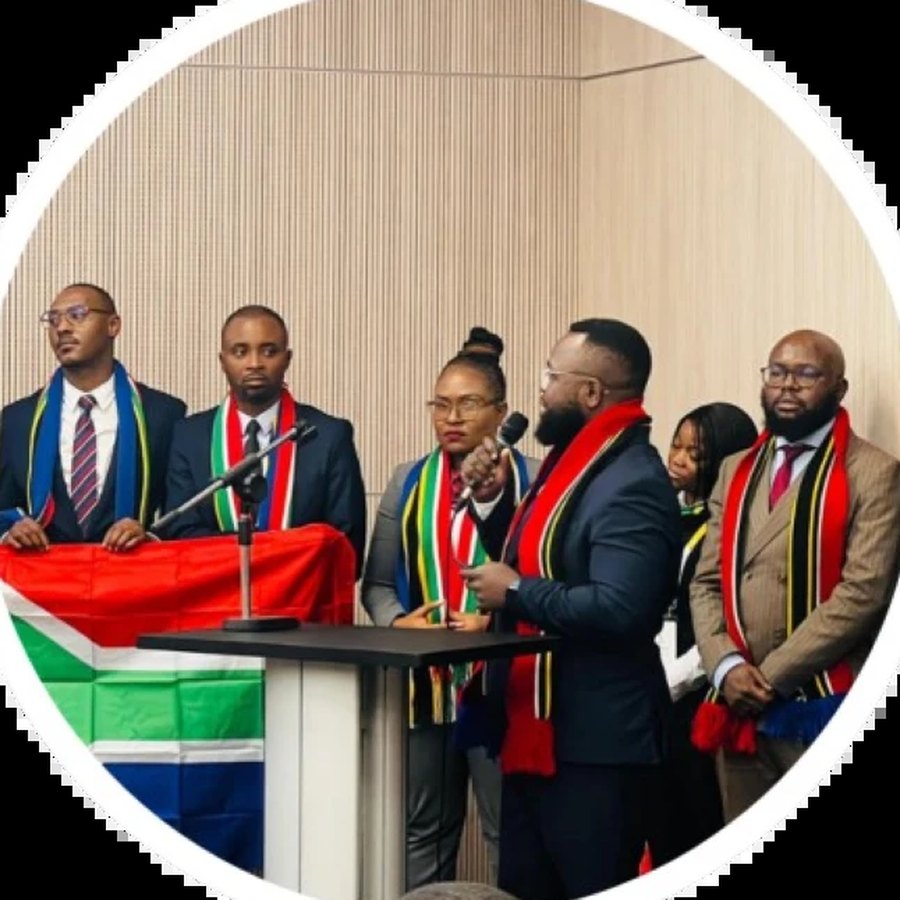 Team JCI South Africa on stage in South African flag scarves, with the South African flag